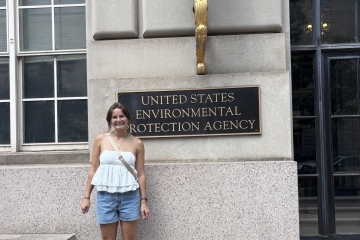 a young white woman stands in front of "US EPA" sign