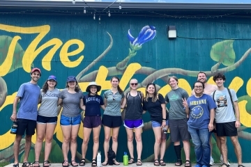 Sustainability Scholars group stands outside against a mural