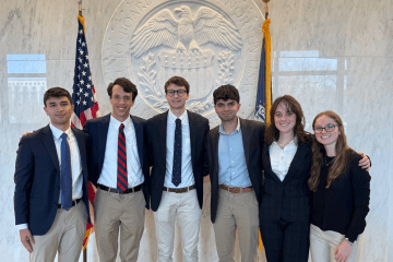 a group of six young people standing in front of the federal reserve building