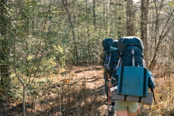 a young woman hiking wearing a backpack in the woods