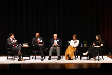 a young man speaks to a panel of alumni on a stage