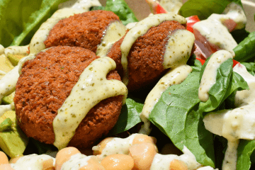 a salad bowl topped with falafel and salad dressing