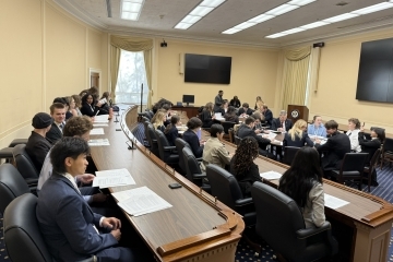 a group of young people sit around in a room working together