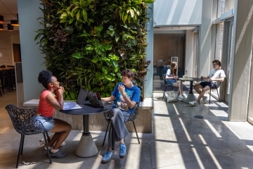 two people meet over laptops and notebooks in a modern academic space
