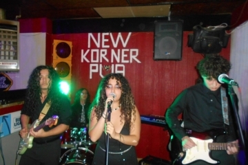 A group of students stand on a dimly lit stage with instruments
