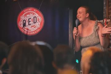 Hannah performs onstage in QUED