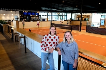 two women stand in front of an indoor pickleball space