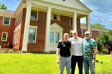 a group of three professors in front of a church on a sunny day