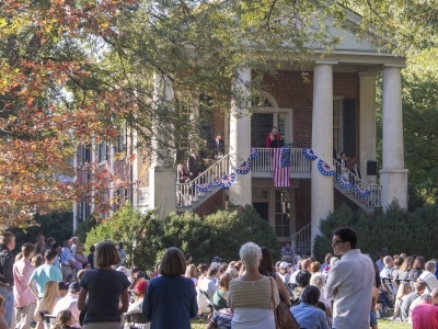 old columned building with people sitting on lawn in front