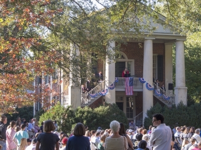 old columned building with people sitting on lawn in front
