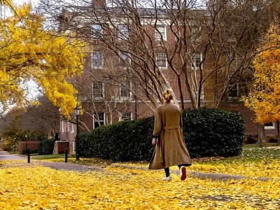 student walking on campus in fall with yellow leaves all around
