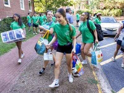 A group of students carry bags in front of a college residence hall
