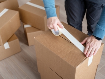 a person sealing a cardboard box with white tape