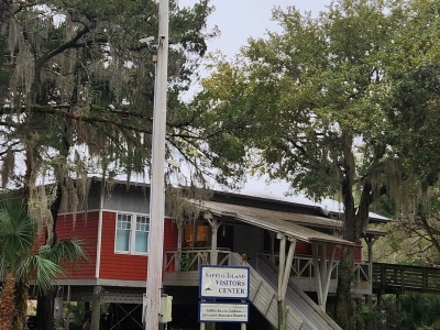 a red wooden building on stilts surrounded by large trees