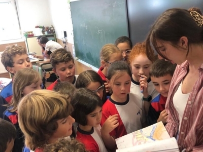 a young woman shows a book to a group of kids