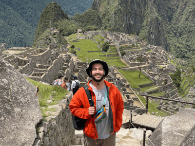 a young man stands on steps overlooking mountains in Peru