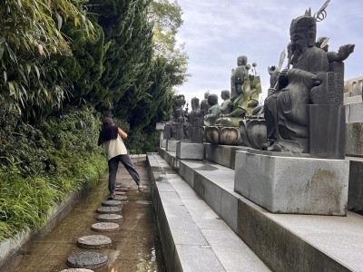 a young woman walks along a stone path at a Buddhist temple