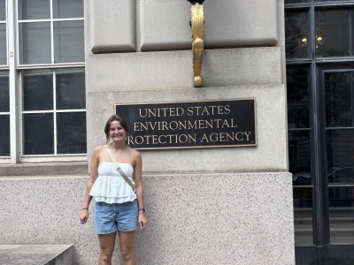 a young white woman stands in front of "US EPA" sign