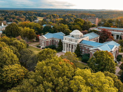 an aerial view of a college campus with brick buildings, green trees and a lake in the distance