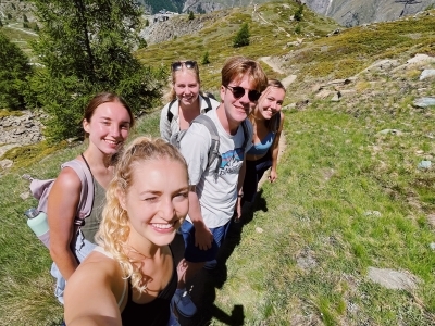 a group of young people take a selfie on the side of Swiss alps