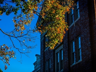 a brick building surrounded by trees changing from green to orange