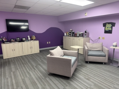  a purple painted room with big chairs and a coffee bar