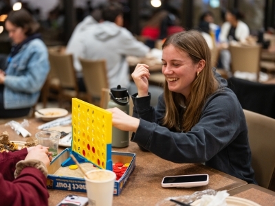 Student laughing and playing Connect Four at the late-night breakfast during finals