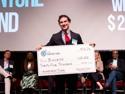 a student holds a giant check at a venture funding competition