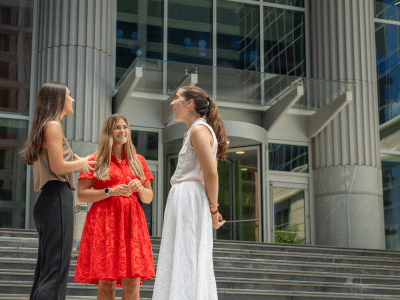 Three female students stand on the steps of the Ally Center in Uptown Charlotte