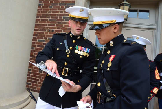 Two ROTC members in formal uniform examine a clipboard while outside