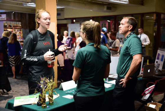Student talks to volunteers from community organization at booth in Union