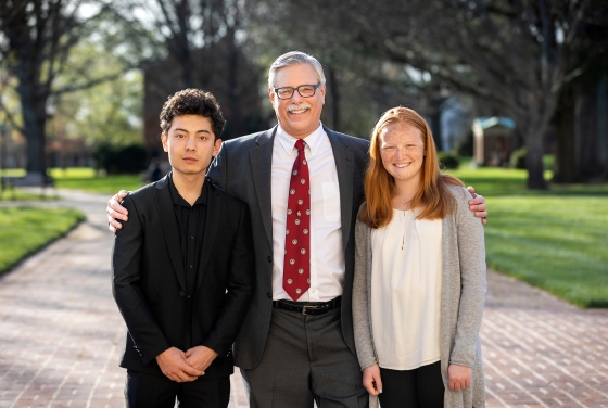 Prof. Emeritus Rich Neidinger outside with two student inductees on his left and right
