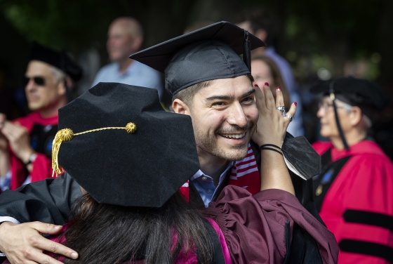 faculty member hugs graduate at commencement 