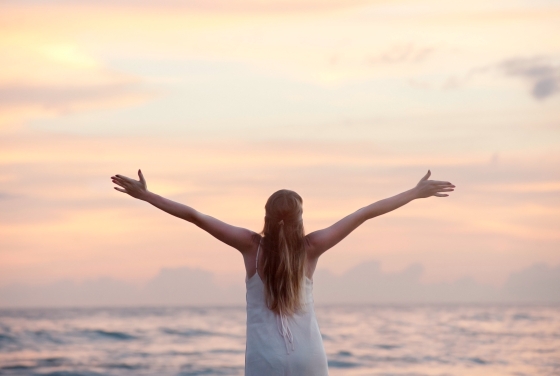 women with arms stretched out at beach stock 