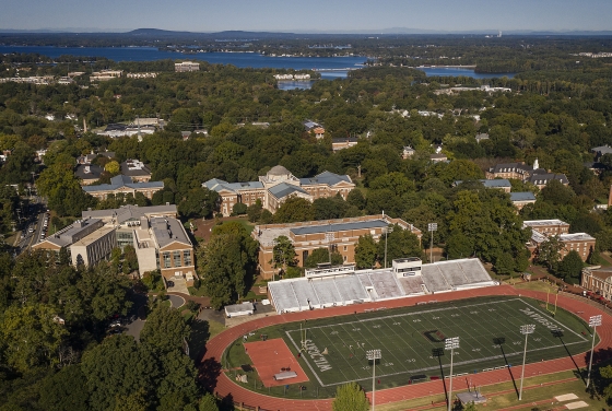an aerial view of Davidson College campus with a football field in the foreground and a lake in the background