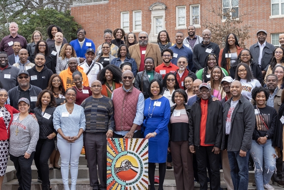 a group of Black folks standing on a set of stairs outdoors and smiling