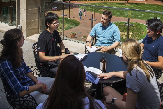 a group of students sit around a table discussing a text