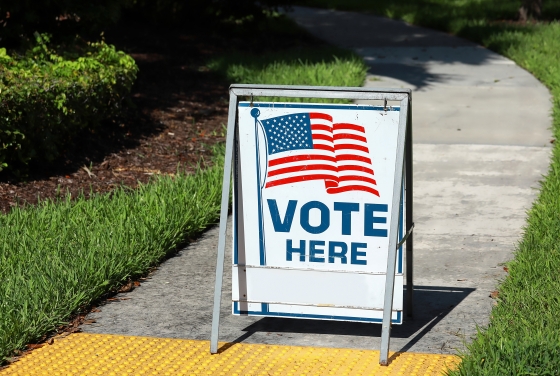 "Vote Here" sign in front of a sidewalk
