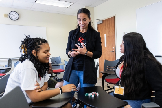a faculty member talks to two students in a classroom