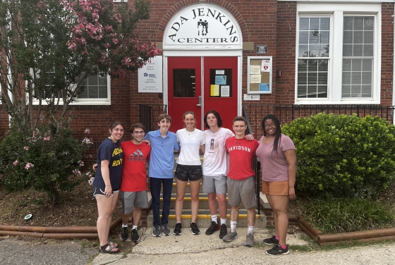 a group of students standing together in front of a brick building that reads "Ada Jenkins Center"
