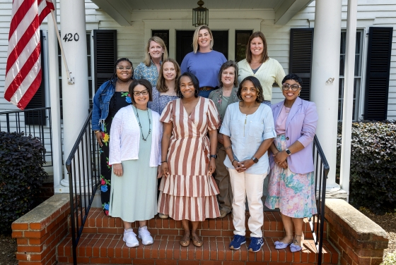 a group of women standing together in front of a historic house