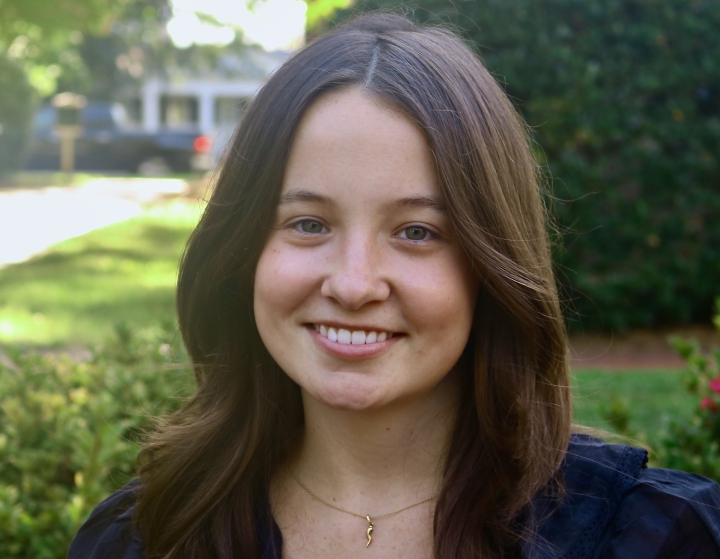 Annalee smiling outdoors with shoulder-length wavy dark hair and a black top.