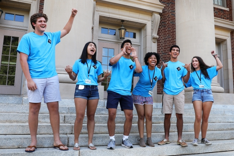 Students in July Experience shirts cheer on the steps of Chambers