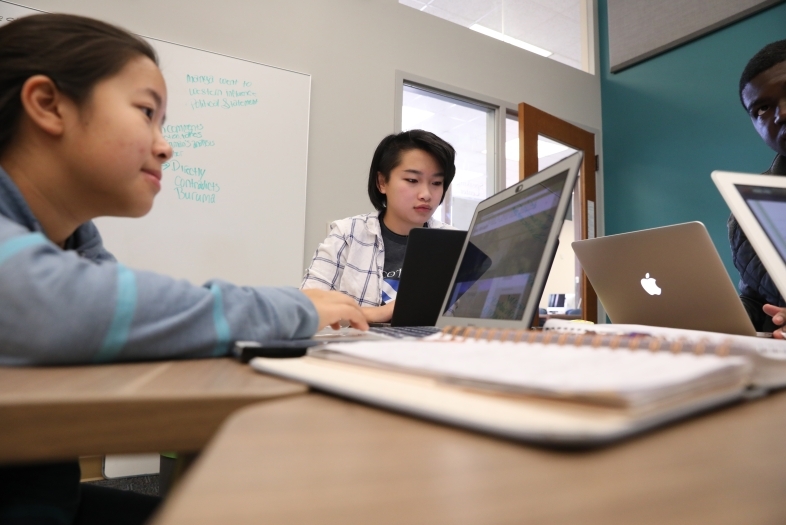 Three students busy working on laptops