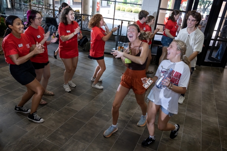 a group of young people in red and white t-shirts smile and cheer for each other