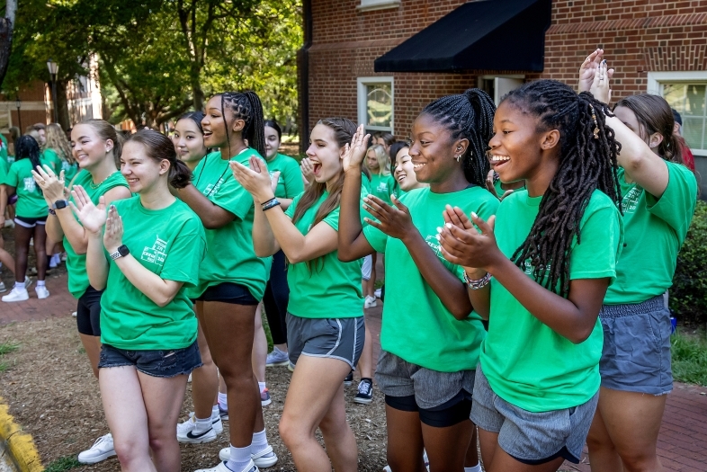 Students wearing green shirts clapping