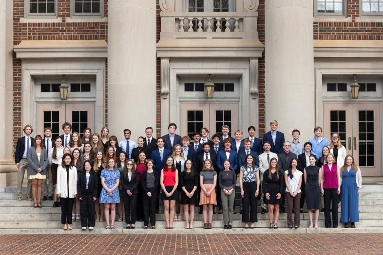 a large group of students standing in front of a brick academic building smiling