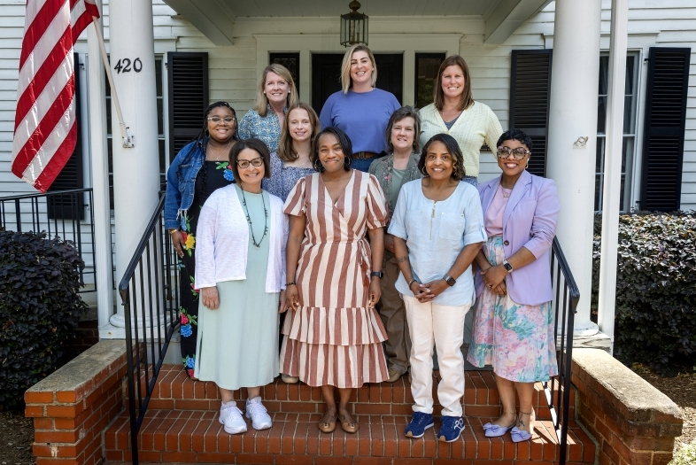 a group of women standing together in front of a historic house