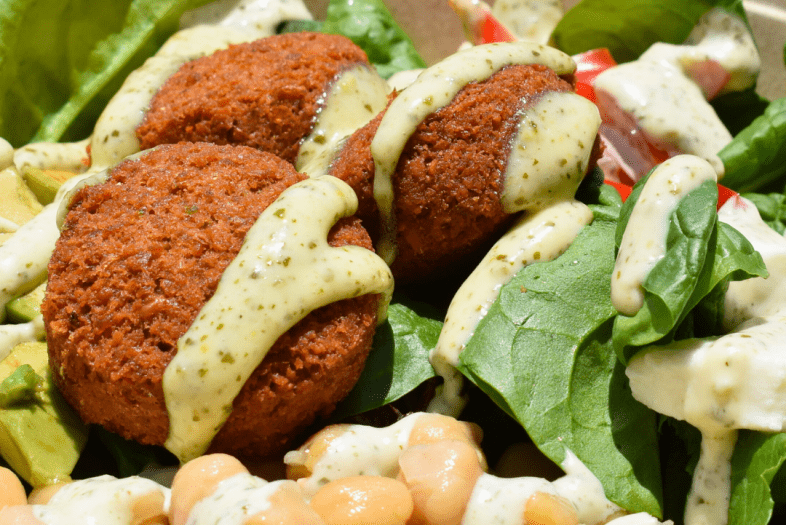 a salad bowl topped with falafel and salad dressing