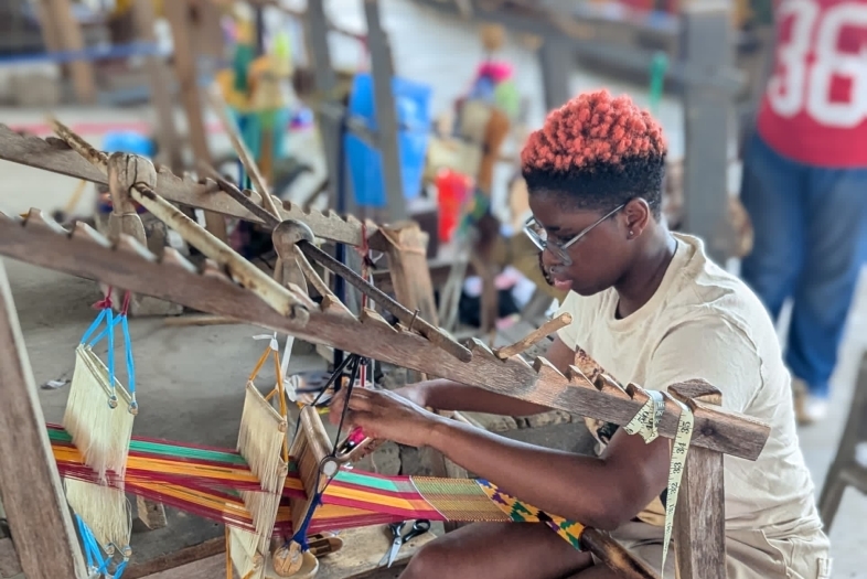 a young person works at a loom 